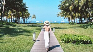A pathway lined with palm trees leading to a beach. - MARINA SEASIDE BOUTIQUE HOTEL (Phu Quoc)