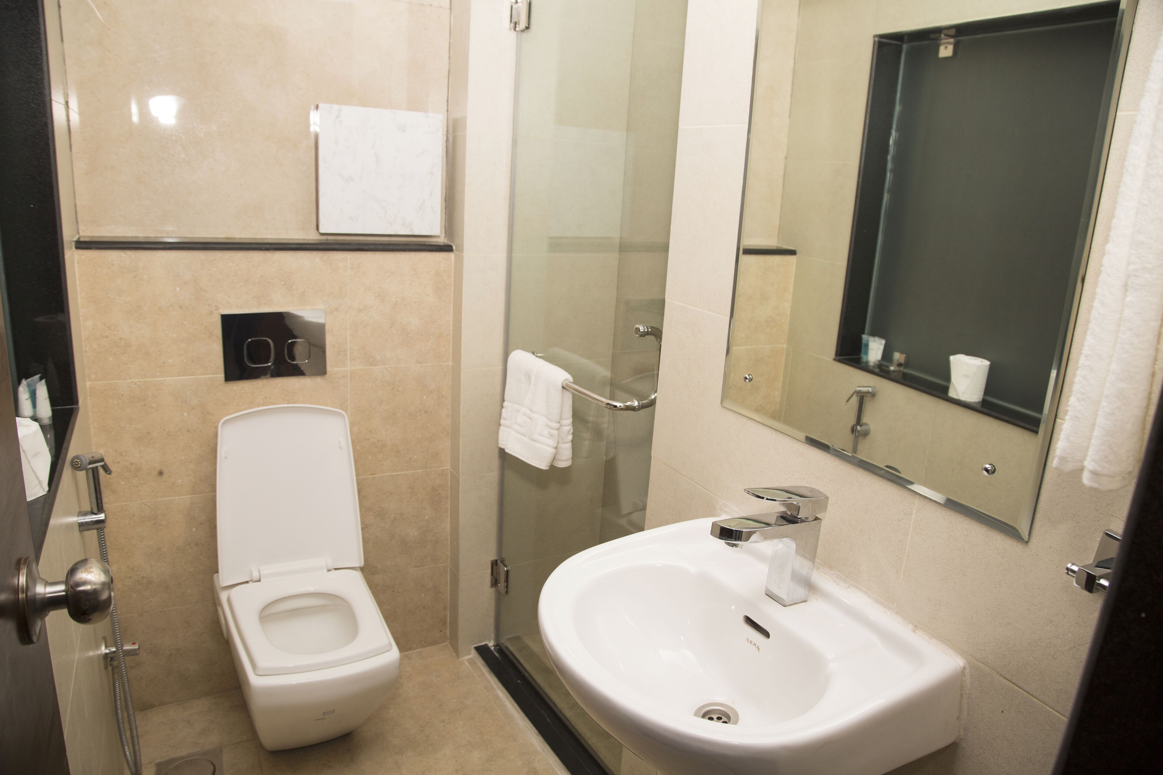 A modern bathroom with a toilet, shower, sink, and mirror.