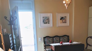 A bedroom with a bed, a table, chairs, and a hanging light fixture.