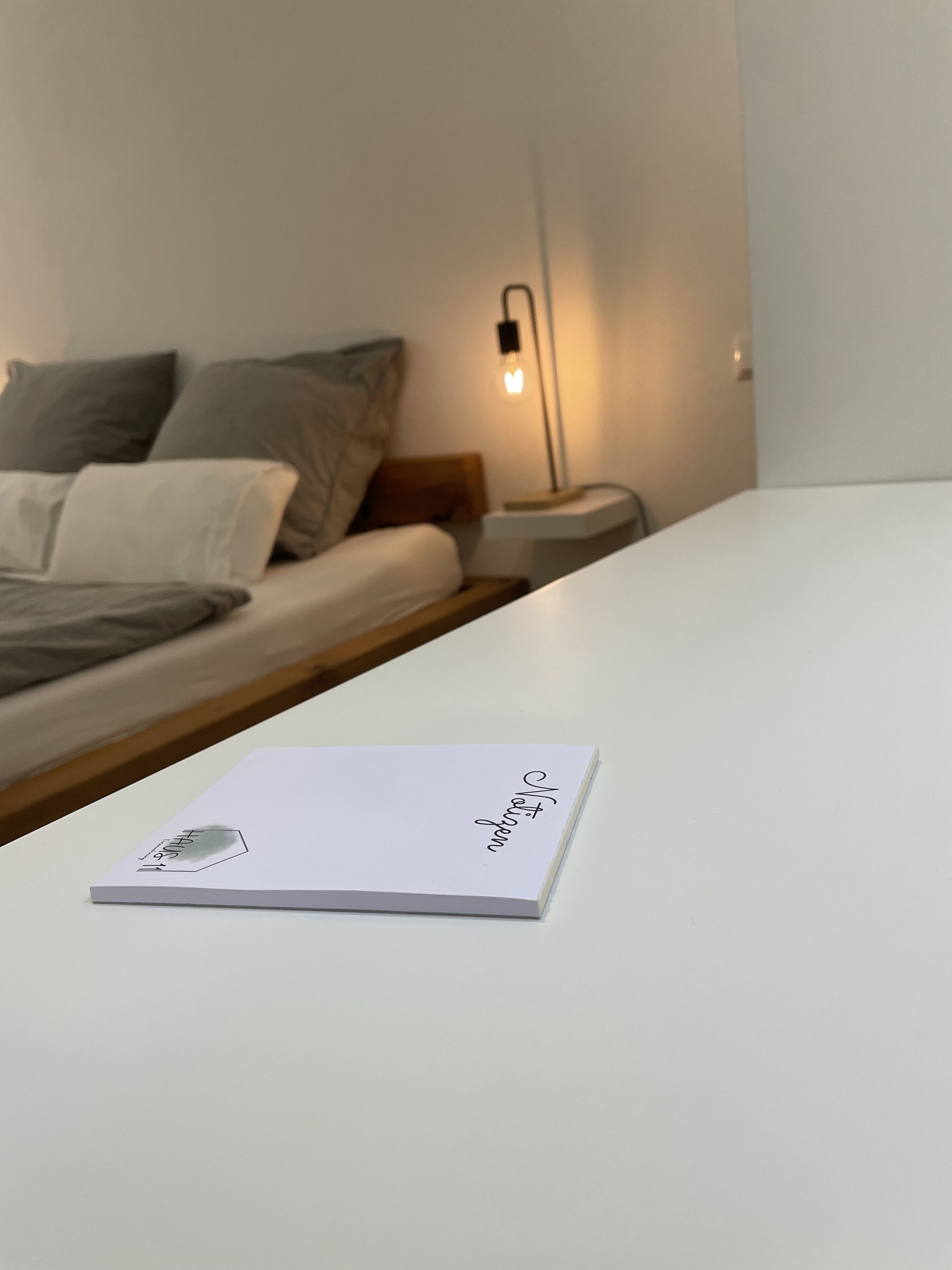 A neatly made bed with pillows and a bedside table with a lamp.