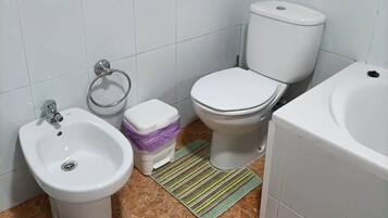 Un baño con bidé, inodoro y lavamanos.