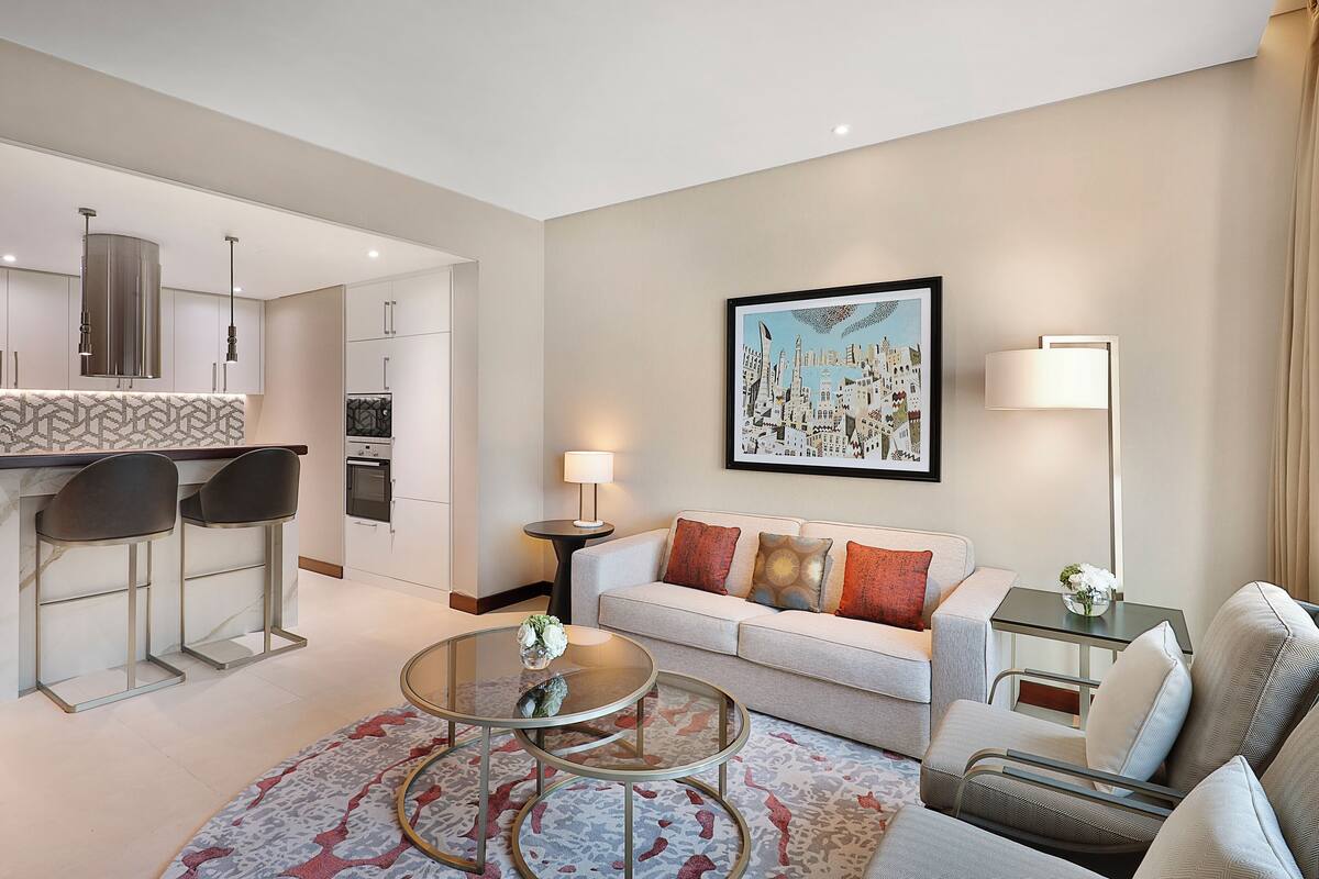 A modern living room with a sofa, a coffee table, and a dining area with bar stools.