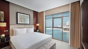 Un dormitorio amplio con una cama grande, vista al mar y una obra de arte enmarcada en la pared.