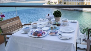 Una mesa dispuesta para una comida, con vista al agua y un edificio al fondo.