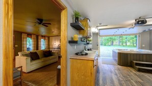 Een moderne keuken met houten kastjes, een ingebouwde kookplaat en een groot raam met uitzicht op een bos.