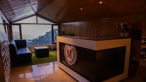 A reception area with a wooden interior, a reception desk with a logo, a sofa, and a view of the outdoors. - Montrose 11 Boutique (Kasauli)
