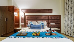 A neatly arranged hotel room with a large bed, a wardrobe, and a bedside table with a bottle and glasses. - Montrose 11 Boutique (Kasauli)