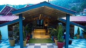 A covered outdoor area with a checkered floor, potted plants, and a wooden structure. - Montrose 11 Boutique (Kasauli)