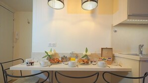 Una mesa con sillas y una zona de cocina con un fregadero y alacenas.