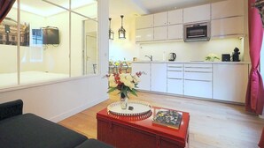 Una cocina moderna con armarios blancos, microondas y cafetera. Hay una mesa de comedor con un jarrón de flores y un libro.