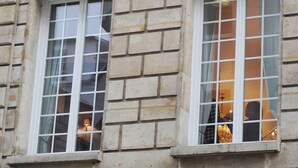 Un edificio con dos ventanas, cada una con un diseño de cuadrícula y marcos blancos.