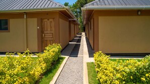 A row of single-story buildings with a central walkway, each with a door and a small window. - KWETU RESORT (Mtwapa)
