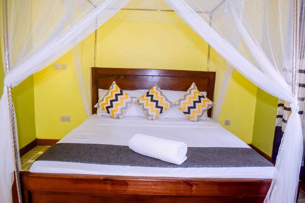 A bed with a wooden headboard, white bedding, and decorative pillows with zigzag patterns.