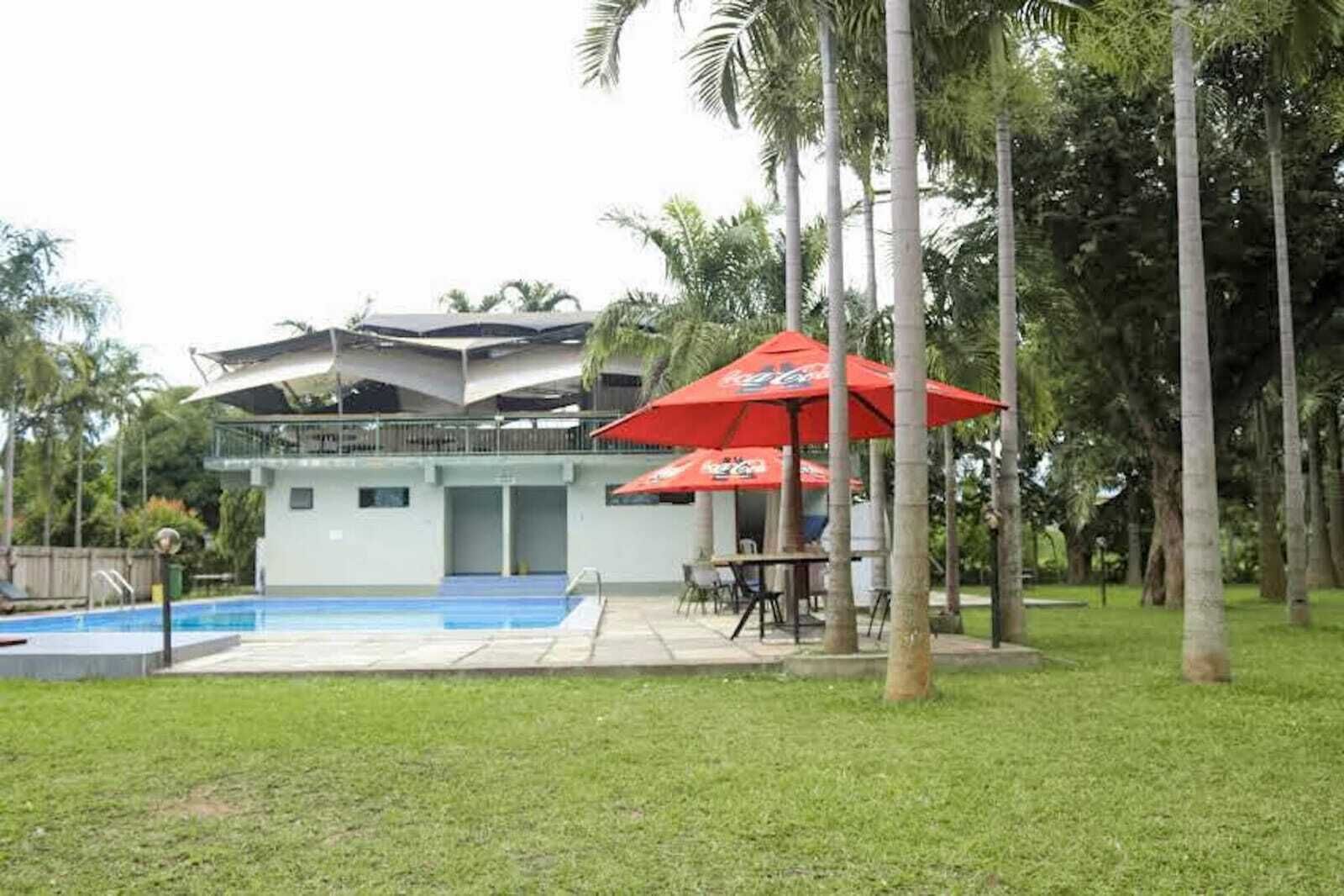 A modern building with a pool, outdoor seating, and palm trees.