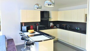 A modern kitchen with a central island, bar stools, and pendant lighting. - Large House in Bude, Cornwall, Sleep18, Quiet Location, Just 10min Walk To Beach (Bude)