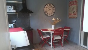 A compact kitchen with a dining area, a clock, and a coffee bar sign. - House in historic center of Caen! (Caen)