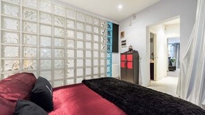 Ein Schlafzimmer mit einem roten und schwarzen Bett, einem weißen und blauen Schrank und einer satinierten Glasscheibe.