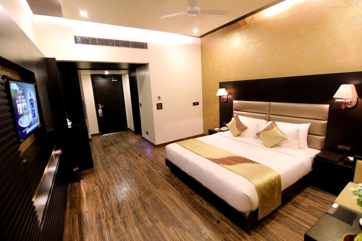 A hotel room with a large bed, a television, a desk, and a ceiling fan.