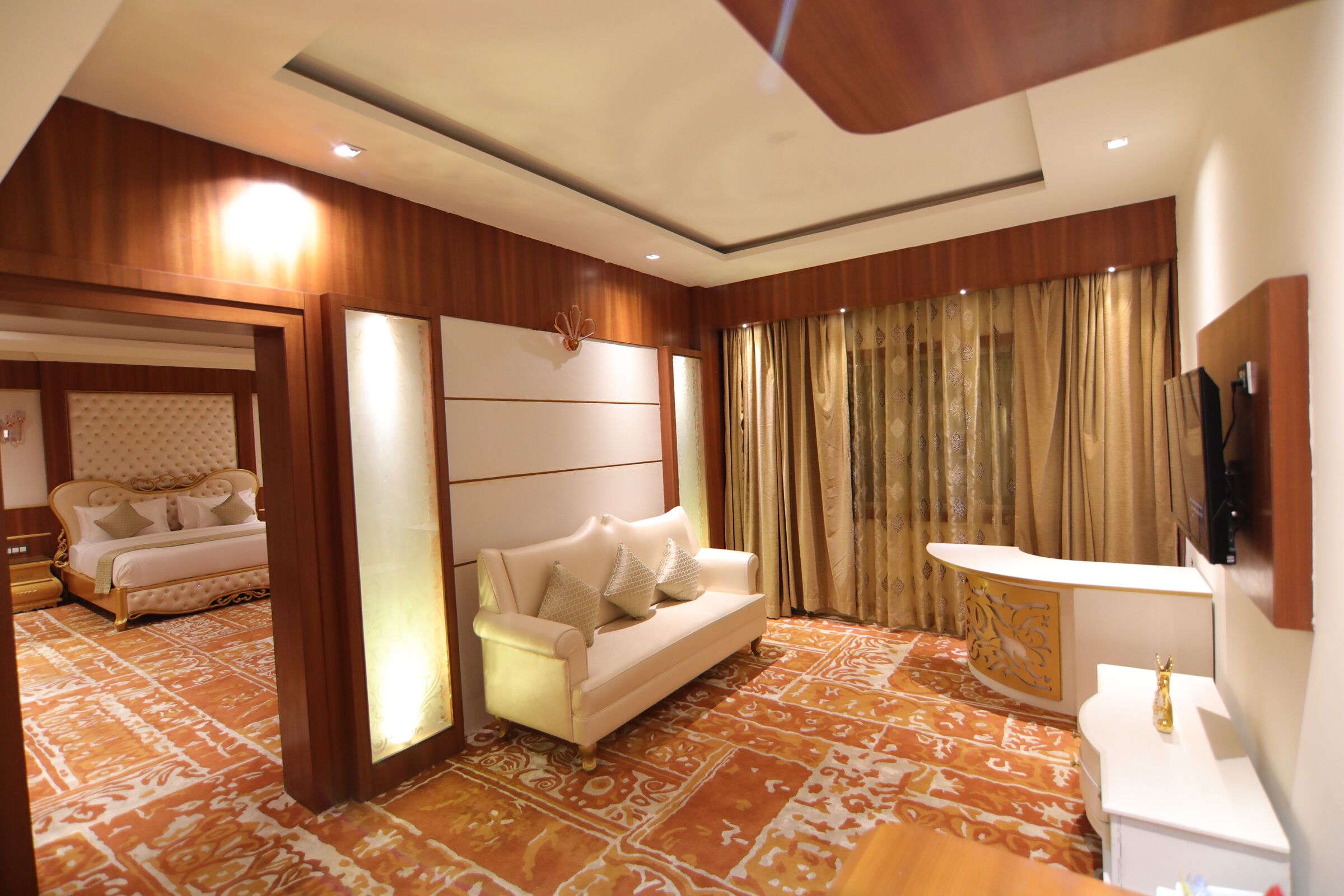 A hotel room with a large bed, a sofa, a TV, and a desk.