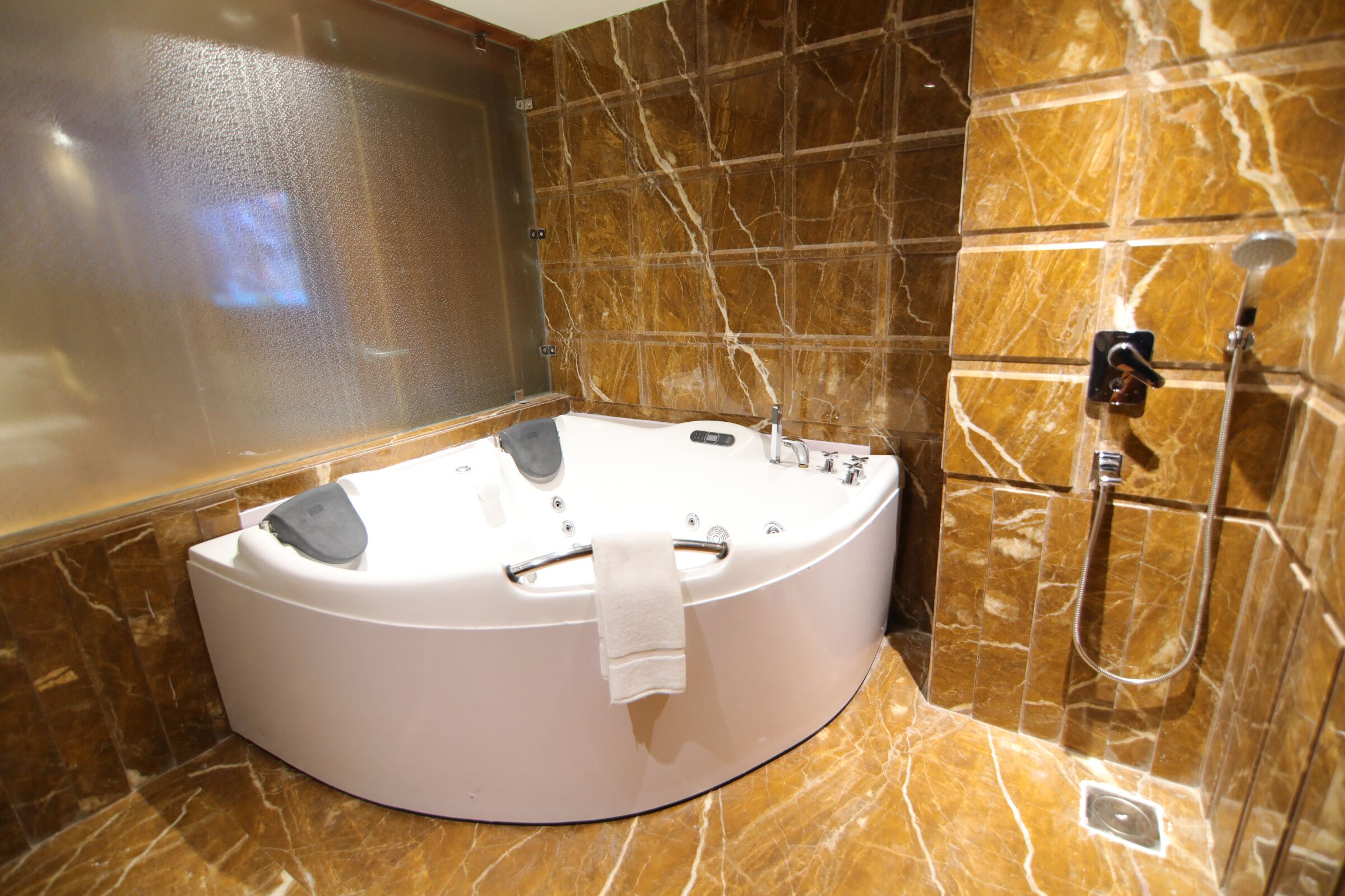 A modern bathroom with a freestanding bathtub, a shower area, and marble walls.