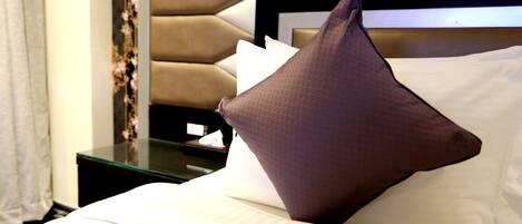 A neatly made bed with a brown pillow and white linens.