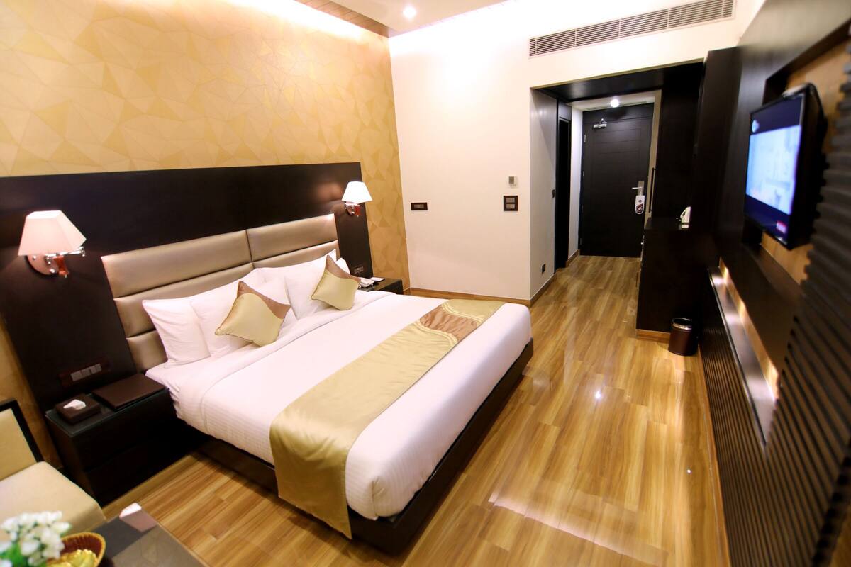 Een hotelkamer met een groot bed, bedlampjes, een televisie en een houten vloer.