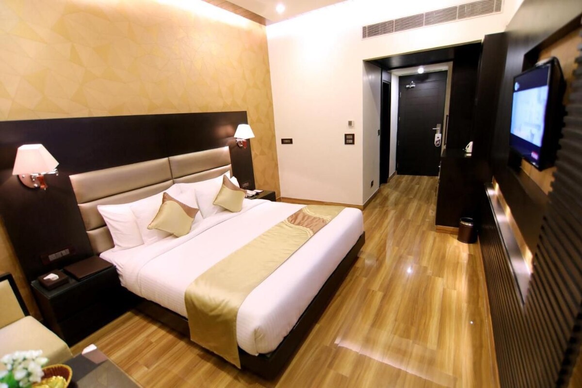A hotel room with a bed, bedside tables, a TV, and a door.