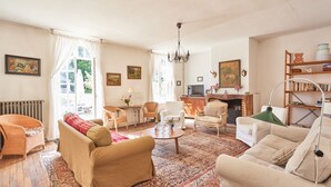 A spacious living room with a large window, a fireplace, and a bookshelf. - The Grand Sambam (Fourdrain)