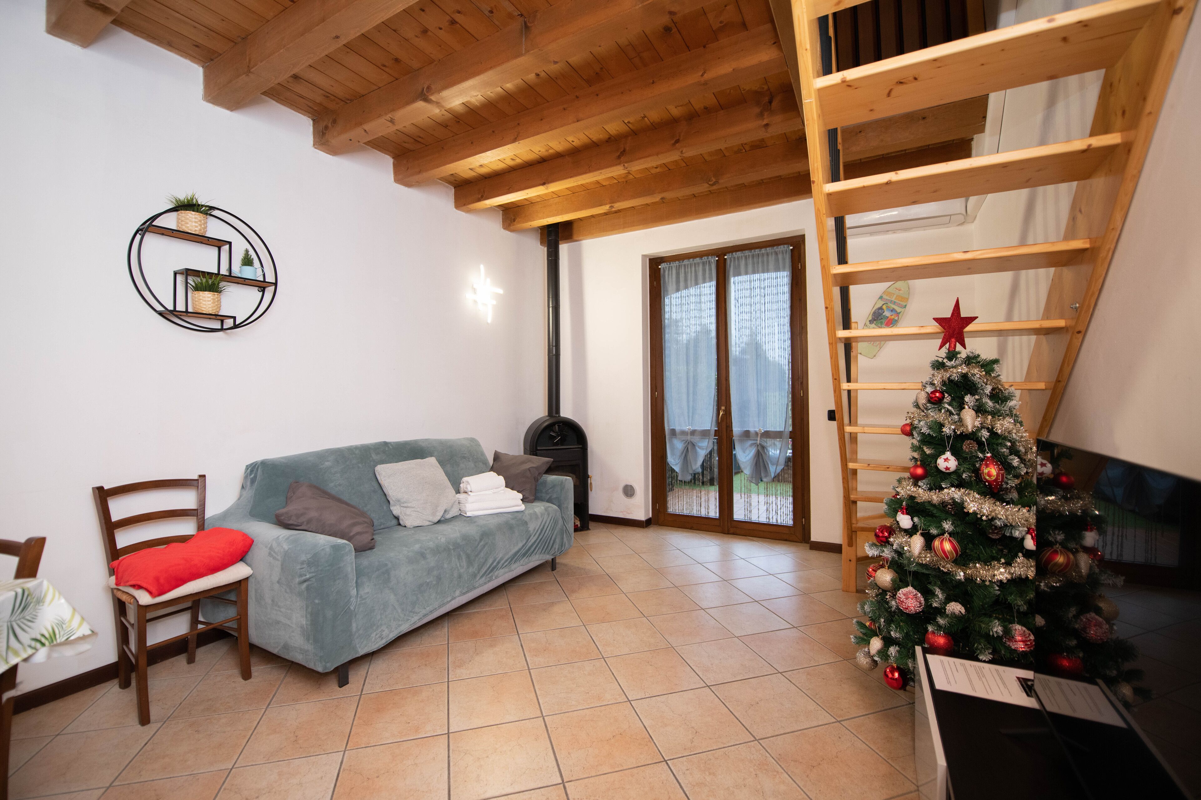 Un soggiorno con divano blu, una sedia in legno e un albero di Natale.