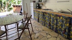 Une cuisine avec un sol carrelé en pierre, une table en bois avec des chaises, un four à micro-ondes et un réfrigérateur.
