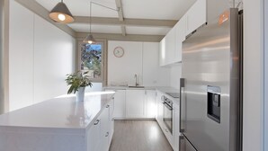 Una cocina moderna con armarios blancos, un refrigerador de acero inoxidable y una lámpara colgante.