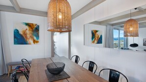 Un comedor moderno con una mesa de madera, sillas negras y lámparas colgantes tejidas.