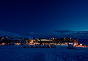 A snow-covered hotel with multiple buildings, ski lifts, and tents.