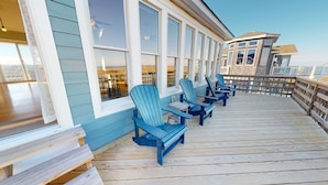 Une terrasse en bois, dotée de chaises Adirondack, et offrant une vue sur l’océan.