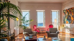 Un salón amplio con ventanas grandes, vista al mar y muebles modernos.