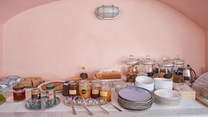 Mesa de desayuno buffet con diferentes alimentos y utensilios.
