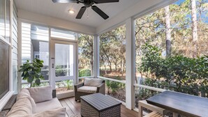 A covered patio with a sofa, two chairs, a table, and a ceiling fan. - Watersound - Golf Cart - Pet Friendly - Bikes (Watersound)