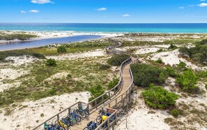 A wooden boardwalk leading to a beach with bicycles parked along it.