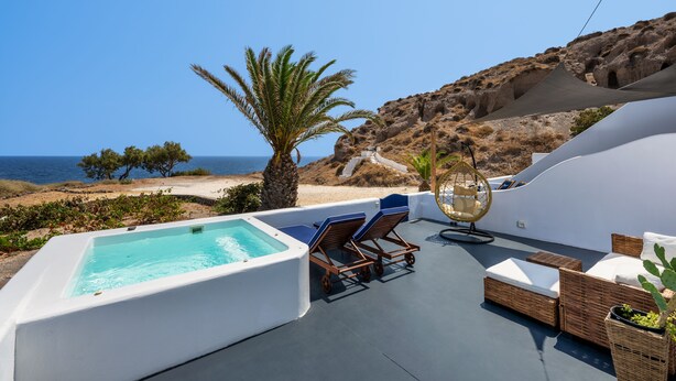 A rooftop pool area with lounge chairs, a hot tub, and a view of the sea. - Pure Seaside Calm, Far from Santorini’s Crowds (Thira)