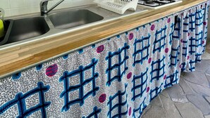 A kitchen with a wooden countertop, two sinks, a microwave, and a decorative wall piece. - Les Vanilles Gite in lush tropical setting, swimming pool 800m from the beach. (Deshaies)