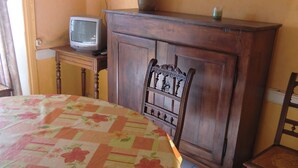 A room with a wooden cabinet, a television on a small table, and a floral tablecloth. - HOUSE IN A SMALL CHARMING VILLAGE: GOOD PRICE-QUALITY RATIO (AUZELLES)