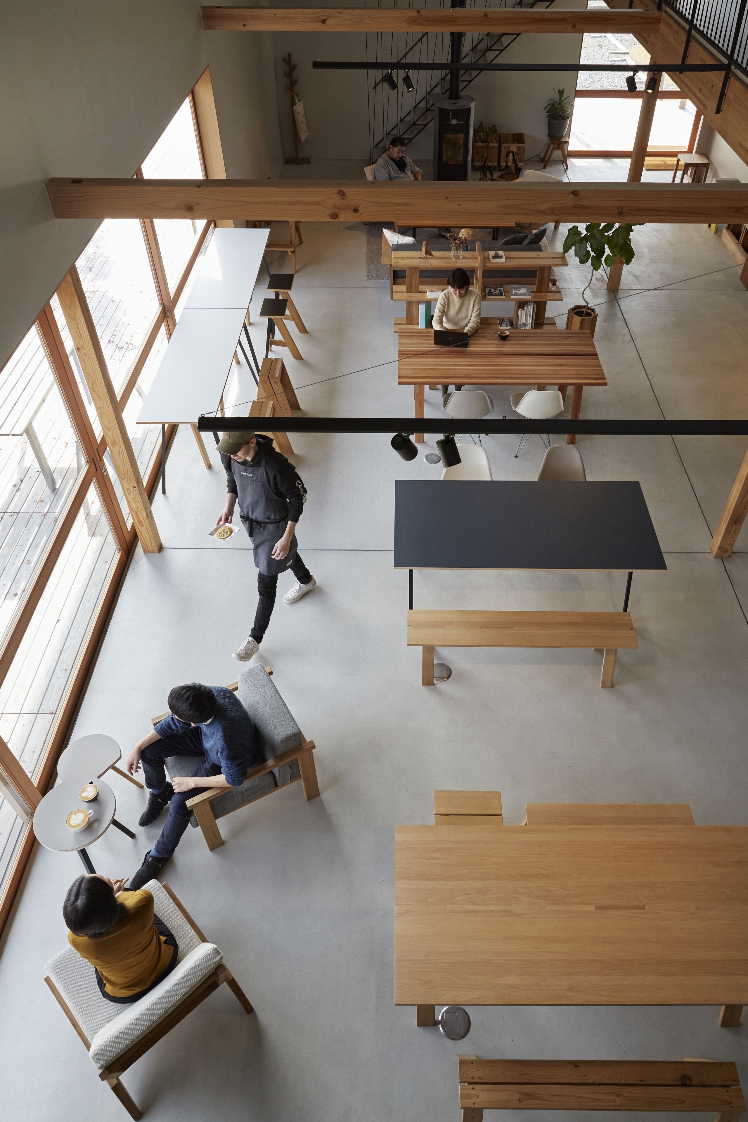 An open-plan workspace with high ceilings, wooden beams, and large windows.