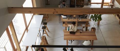 An open-plan workspace with high ceilings, wooden beams, and large windows.