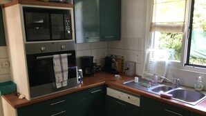 A kitchen with a microwave, oven, coffee maker, and a window with a view of greenery.