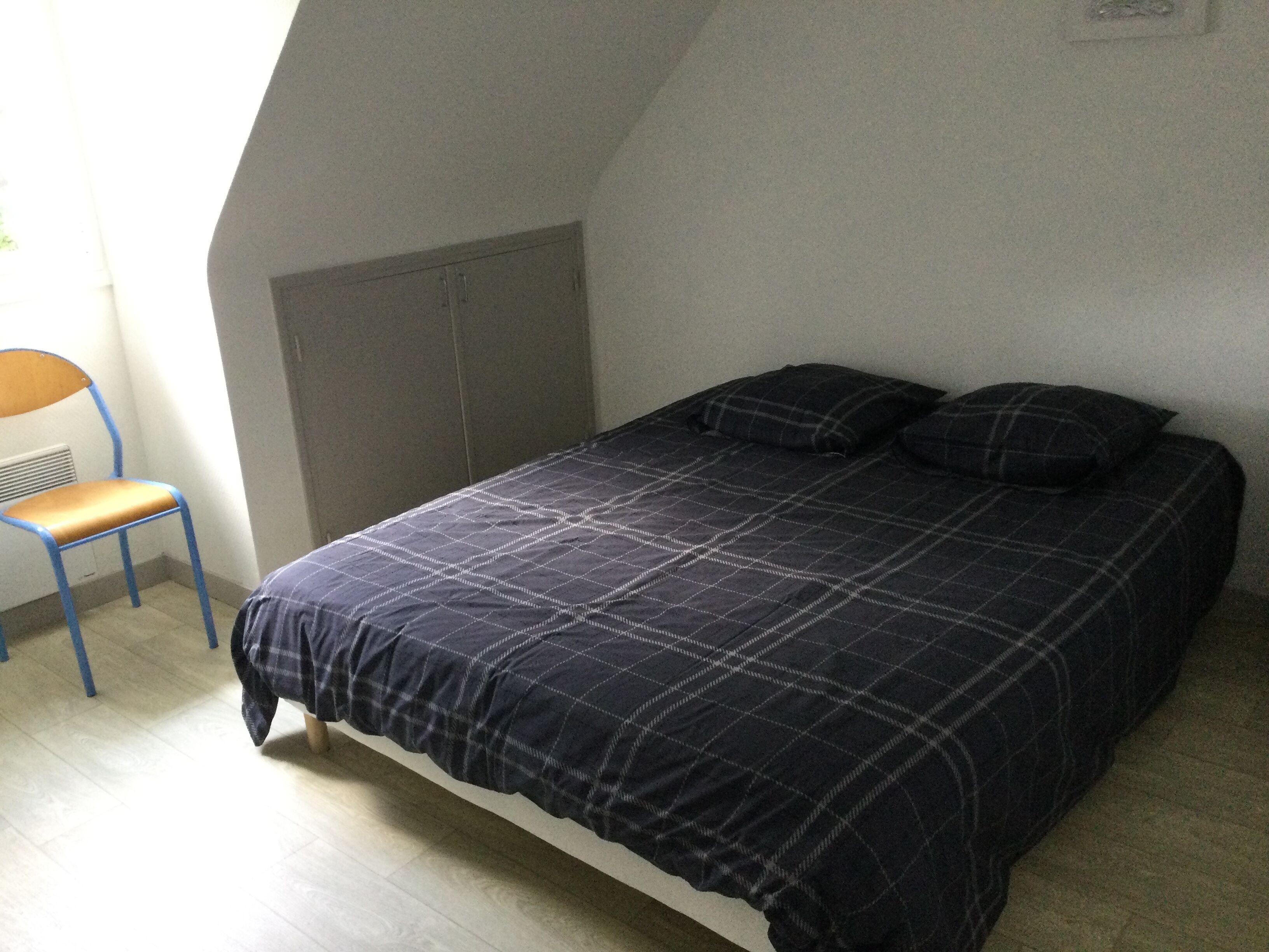 Ein Schlafzimmer mit einem Bett, einem Sessel und einer Heizung.