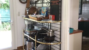 A kitchen with a metal rack holding pots and pans, a hanging light fixture, and a door leading to a balcony.