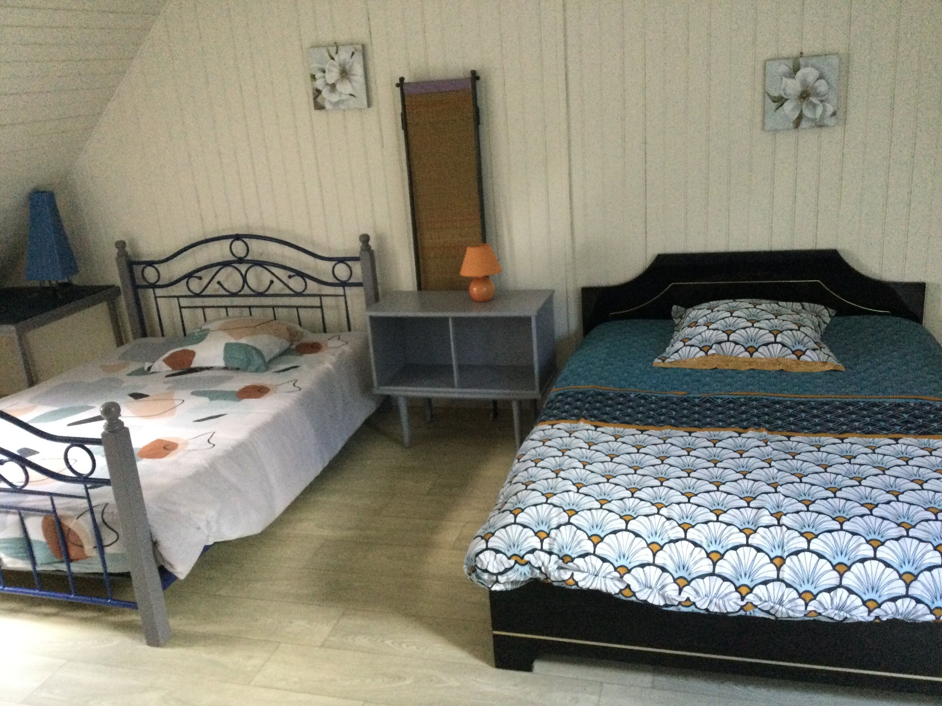 Une chambre avec deux lits, une table de chevet et une commode.