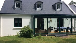 A house with a covered porch, a small garden, and a window with a view of the interior.
