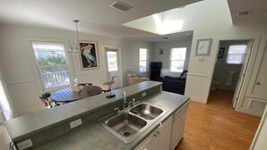 A modern kitchen with a large island, stainless steel sink, and a view to the living area. - Cottage with Boat Dockage, Steps to Private Beach Access! (St. Augustine)