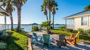 A beachfront property with a covered dock, outdoor seating area with Adirondack chairs, and a view of the water. - Cottage with Boat Dockage, Steps to Private Beach Access! (St. Augustine)